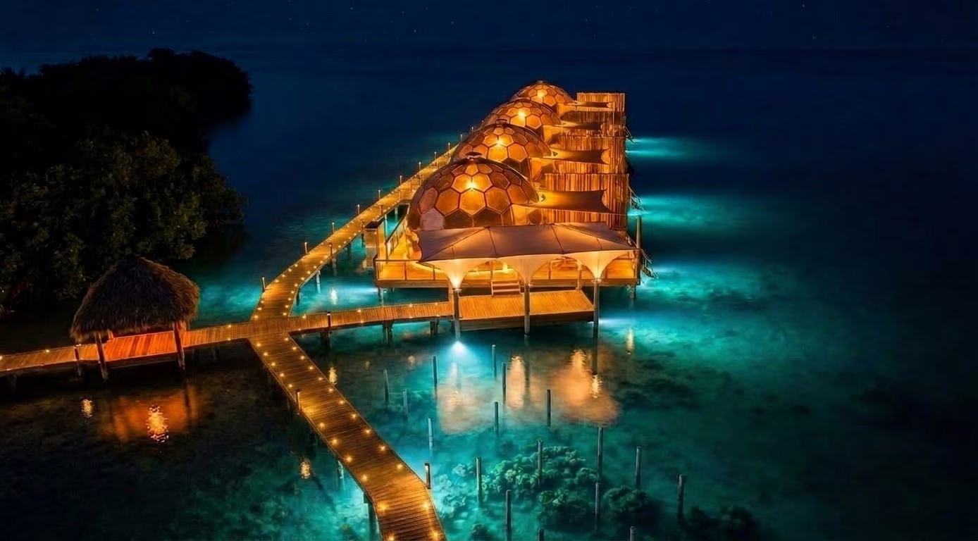 Overwater glamping domes glowing at night above the Caribbean